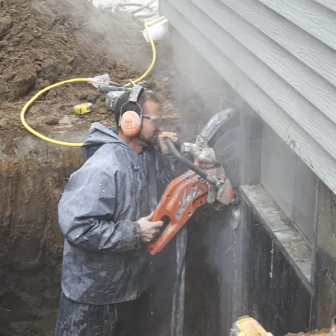 man cutting basement wall 