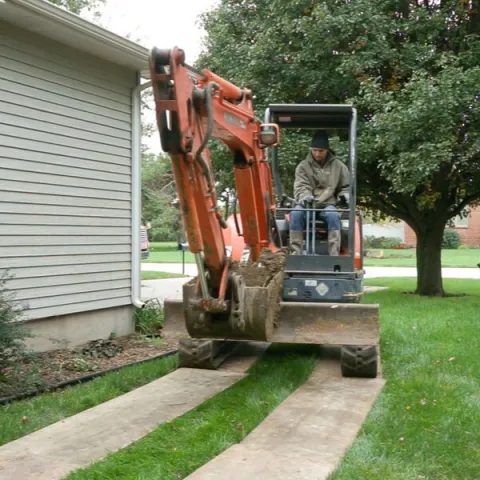 man driving an excavator over a protected lawn